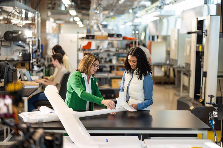 A student and a professor work on an airplane model in a lab