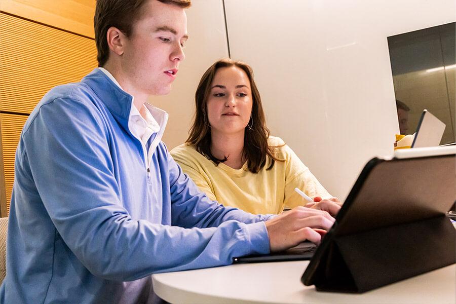 Two students sitting at a desk looking at a computer